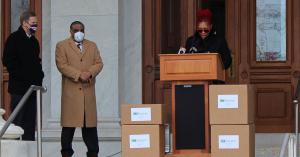 Nichelle Mullins of Charter Oak Health Center speaks to reporters while standing at a podium.