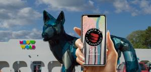 hand holding smartphone phone in front of old bowling alley with a giant dog in front