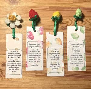 Strawberry printed bookmarks with detachable hand-felted strawberry charms, featuring four stages of the strawberry plants life cycle.