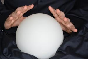 Two hands over a crystal ball on a black satin backdrop