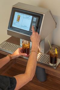 Bartender using Easybar Automated Cocktail Station to make a Long Island Iced Tea by selecting the drink on a touchscreen