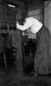 Photograph by Lora Webb Nichols of Mary Anderson brushing her long hair in a wood cabin in Encampent, Wyoming.