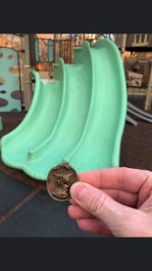 Winner holding tin badge worth $10,000 in front of slide where it had been hidden