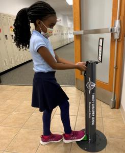 school aged girl using sani-jr hand sanitizer dispenser for kids