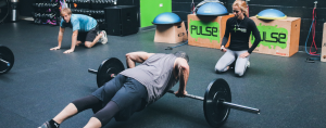 Personal trainer at Pulse Fitness HP oversees a man lifting weights.