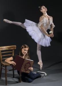 Young girl reading the classic book Sleeping Beauty while a beautiful ballerina in a tutu dances next to her