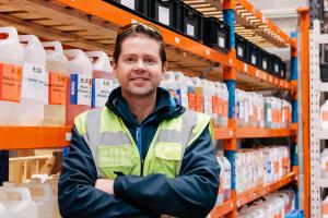 Dr Adam Hunniford of PiP Chemicals in Newtownards, Northern Ireland, UK. Adam is standing in his warehouse beside a shelving unit of chemicals.