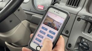 Driver holding phone running the QuickLoadz Remote Web App from inside the truck cab