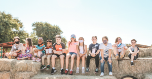 Students sitting on hay bales at local farm