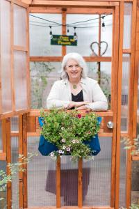 Debra Prinzing stands in her personal greenhouse, which inspires her to profile other floral professionals in Where We Bloom (c) Missy Palacol