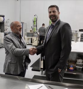 Mark and Joe shaking hands in a factory