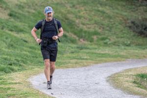 Man wearing hat running 750 miles while carrying a 25-pound slam ball on his back.