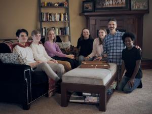 Asa, Abel, Gillian, Stella (a German Shepard dog), Ellie, Lily, Ben, and Ben Jr., sitting on a couch together [Anabel not pictured]