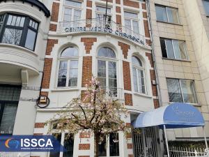 The ISSCA has officially opened their Uccle, Belgium Stem Cell Center, pictured here with hte ISSCA logo in the bottom left. A row of old apartment buildings with a business logo on the bottom left.