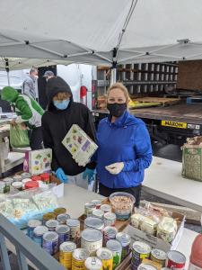 Masked young man and mom organizing canned goods from truck during pandemic.