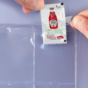 A hand is flipping open the top flap and inserting a ketchup packet.