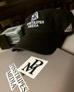 Pinstripes Media logo on a laptop and baseball cap.