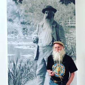 Dean Evenson stands next to large image of Claude Monet; both have impressive white beards.