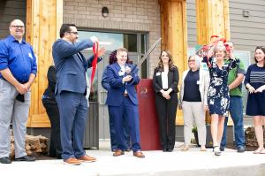 Group gathers around in front of Astral at Auburn senior living community to cut ribbon during open house.