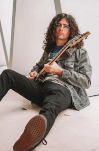 Nick Brodeur sat on the floor with his electric guitar and Lennon style glasses.