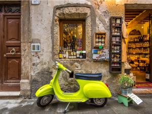 Neon Vespa in front of historic, small Italian shop.