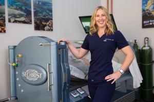 Nicole Garrett next to a Hyperbarics Chamber