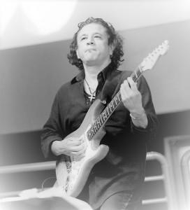 Joe Calderon in black and white playing the electric guitar.