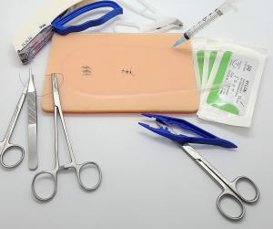 This is an image of a suture kit. This kit shows the suture pad, the suture tools,  sutures and a surgical skin stapler.