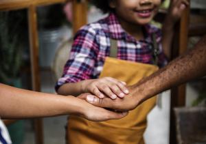 Two adults supporting a child and working together.