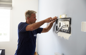 Ein Mila-Techniker installiert eine Wandhalterung für einen Smart-TV.