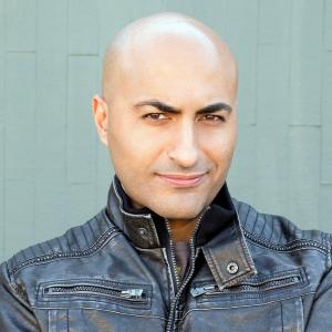 Headshot of Slim Khezri wearing a leather jacket and shaved head.