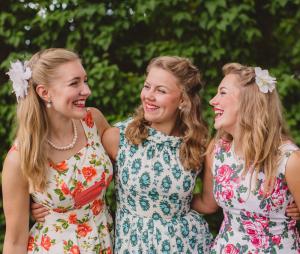 The three Hebbe Sisters wearing flowery 50's style dresses.