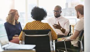 African American man is talking to a group of three diverse colleagues.