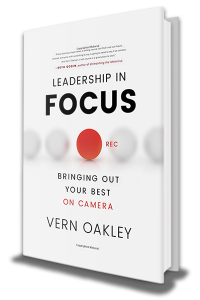 A white book with black text that reads "Leadership in Focus: Bringing Out Your Best On Camera," written by Vern Oakley. There is a red circle in the center with the text "rec" to mimic a recording light on a camera.