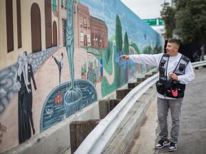 Muralist JP Reyes points out some of the features in the new Hollywood’s Village mural.