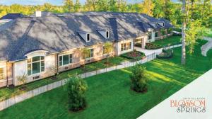 Blossom Springs building with wood landscape, green grass & private walking path in a secure environment.