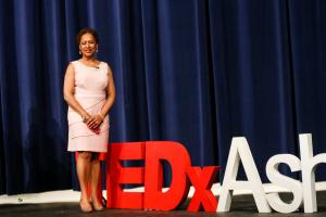 Tanja Thompson standing next to a 3D display that says TEDxAshburn after delivering her powerful TEDx Talk "From Tragedy to Triumph"