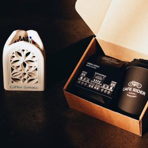 The unique Qamaria lantern beside a limited edition Cafe Rider gift box containing a bag of Yemen Haraz coffee and a reusable coffee cup.