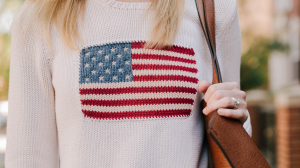 Women wearing a knitted sweater with an American flag on it.