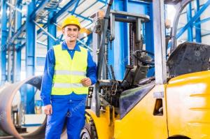 Forklift operator standing beside his forklift in a warehouse