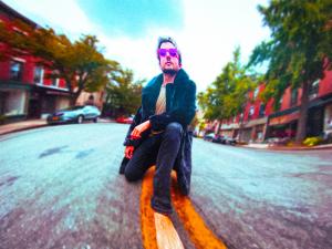 Music composer Frank Cogliano kneeling in the middle of Atlantic Avenue in Brooklyn