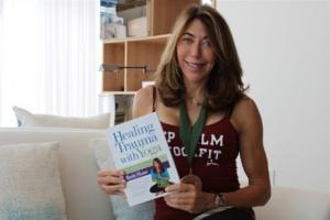 Beth Shaw holds a copy of her book Healing Trauma with Yoga.