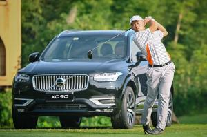 Chinese golfer hitting a golf shot in front of a Volvo car