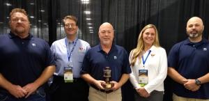 The Heartland Pet Food Mfg. lubrication team holds the Battle Award trophy while posing with ICML reps.