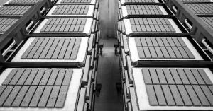 Black and white image of Biomason bioLITH biocement tiles arranged on racks to cure in a factory.