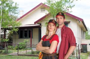 A DIY Couple in Asbestos Awareness hats are outside a home which contains asbestos