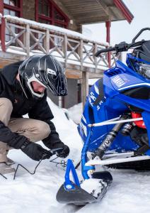 Man holding CTEK CT5 POWERSPORT charger next to a snowmobile
