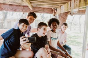 Friends snap a picture on the Pinwheel smartphone while playing in a treehouse.