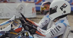 Ellis & Axel are side by side in their karts with helmets on and ready to race.