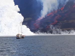 Volcanic eruption in Galapagos with lava entering the sea includes ship